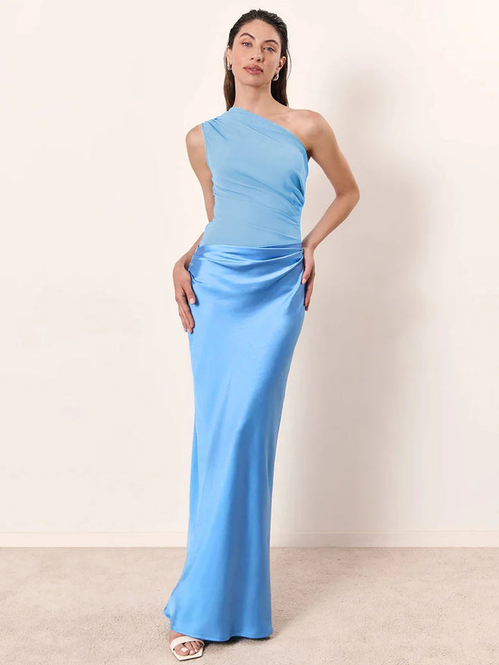 Woman wearing a light blue one-shoulder gown against a plain background