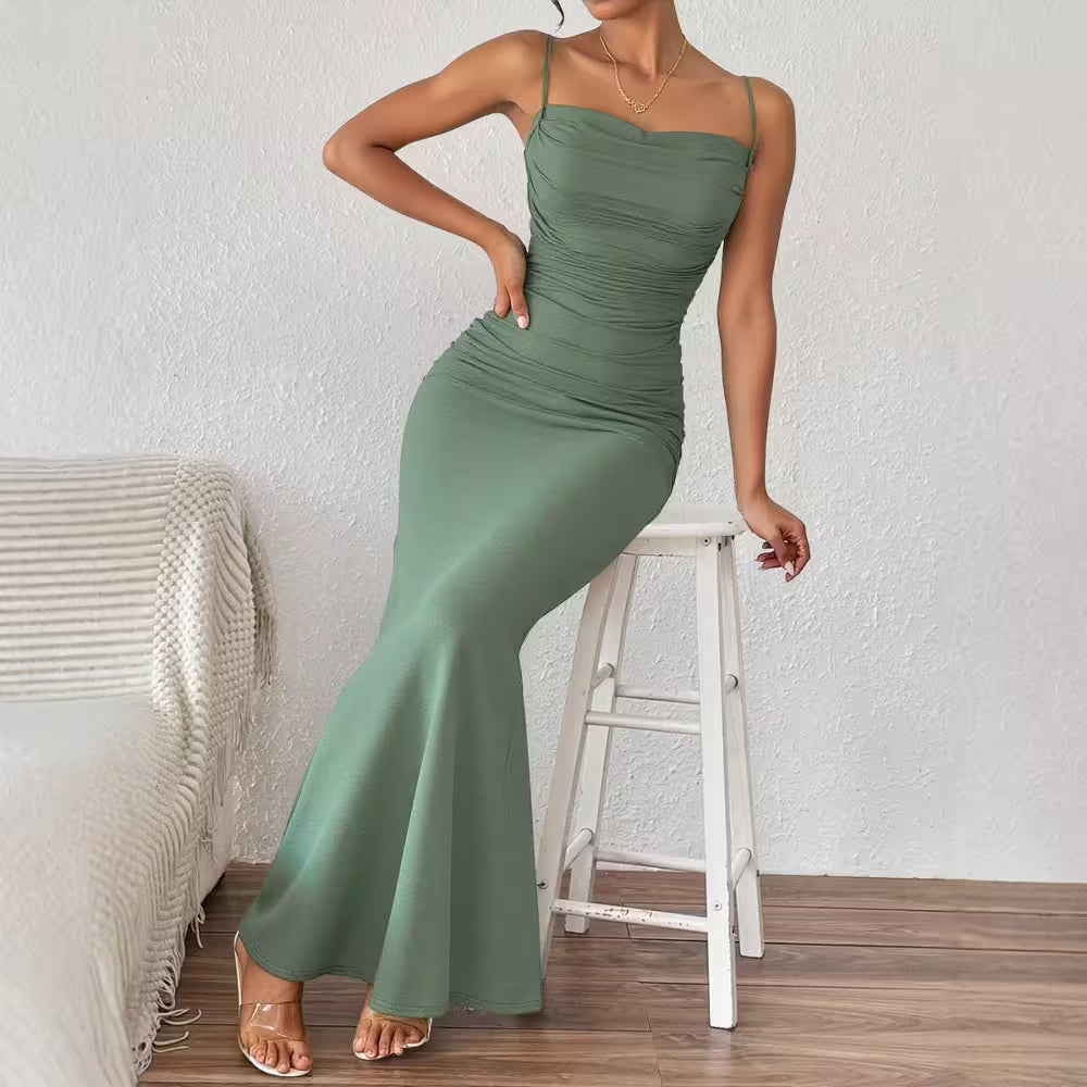 Woman wearing a green dress sitting on a white stool against a white wall.