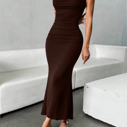 Woman wearing a brown dress standing in a modern indoor setting with white furniture.