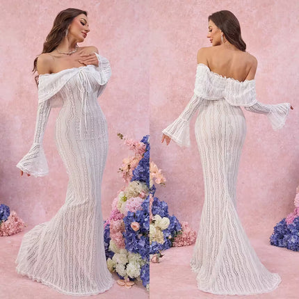 Woman wearing a white off-shoulder lace gown with floral decorations in the background.