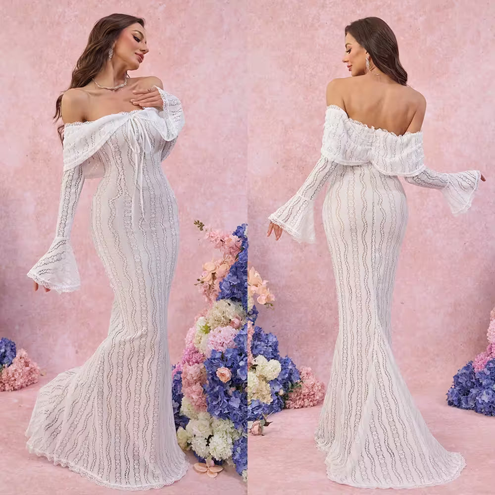 Woman wearing a white off-shoulder lace gown with floral decorations in the background.