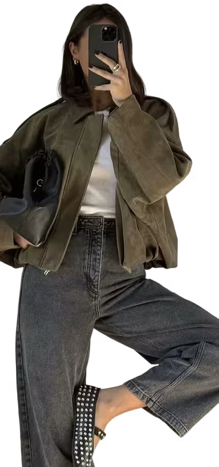 Person wearing a green jacket and jeans, holding a phone.